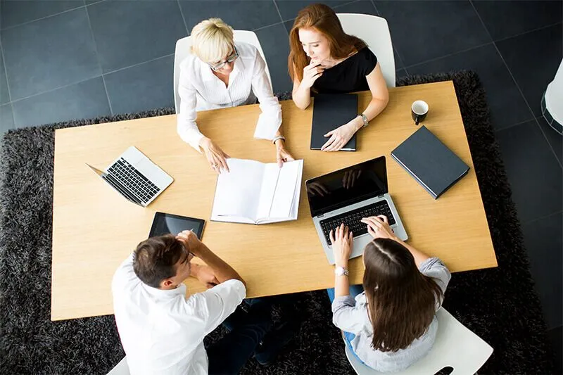 Top view of a team working with laptops and documents at a meeting table